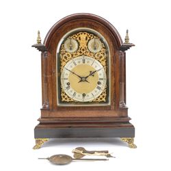 Winterhalder and Hoffmeier - German 8-day three train Edwardian oak cased mantle clock, with a break arch pediment, brass sound frets to the sides and conforming glazed door beneath, with flanking reeded pilasters on a stepped plinth raised on paw feet, sheet brass dial with fretted spandrels and matted dial centre, silvered chapter with Roman numerals, gothic steel hands and subsidiary dials for pendulum regulation and chime select, going barrel movement, chiming the quarters and striking the hours on nine coiled steel gongs. With pendulum and keys.