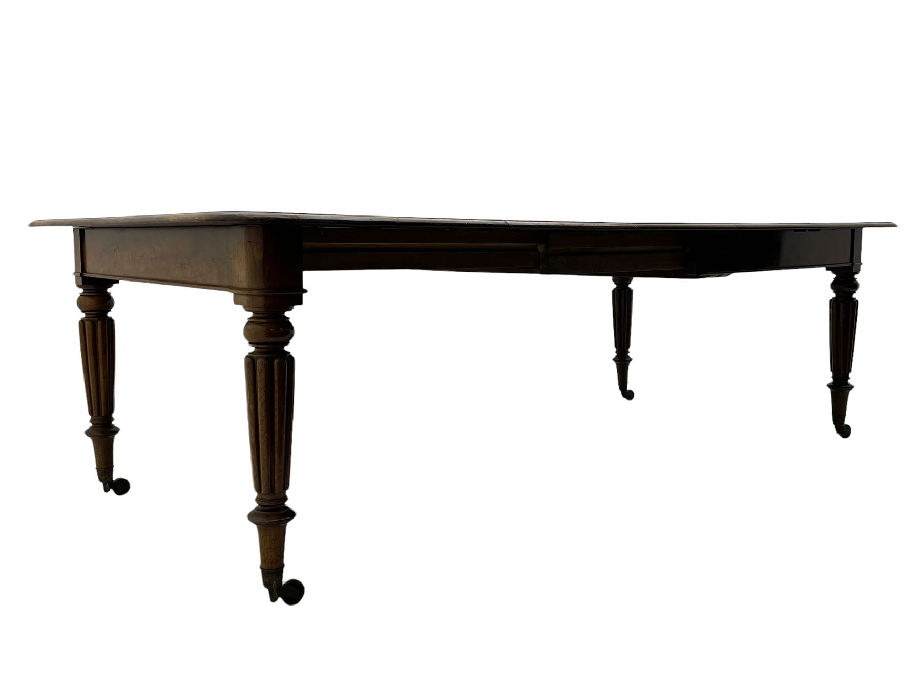 Early 19th century figured mahogany extending dining table, the rectangular top with moulded edge and rounded corners, pull-out action with three additional leaves, raised on turned and lobe carved supports with brass cup castors