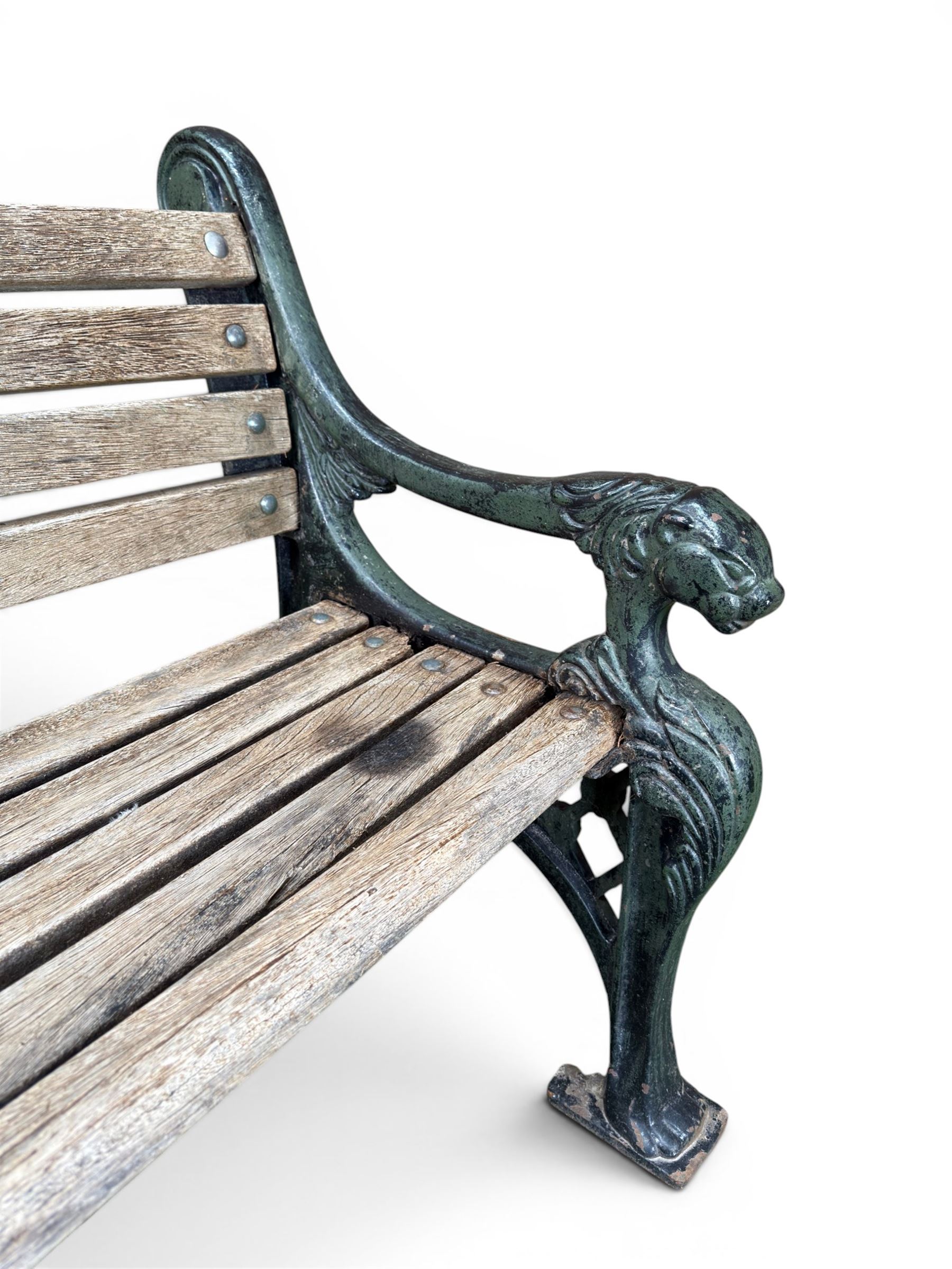 Neoclassical design cast iron and oak slatted garden bench, the twin end supports in the form of a Sphinx with acanthus carved knees and large paw feet, the pierced lattice bracket with Yorkshire rose motifs