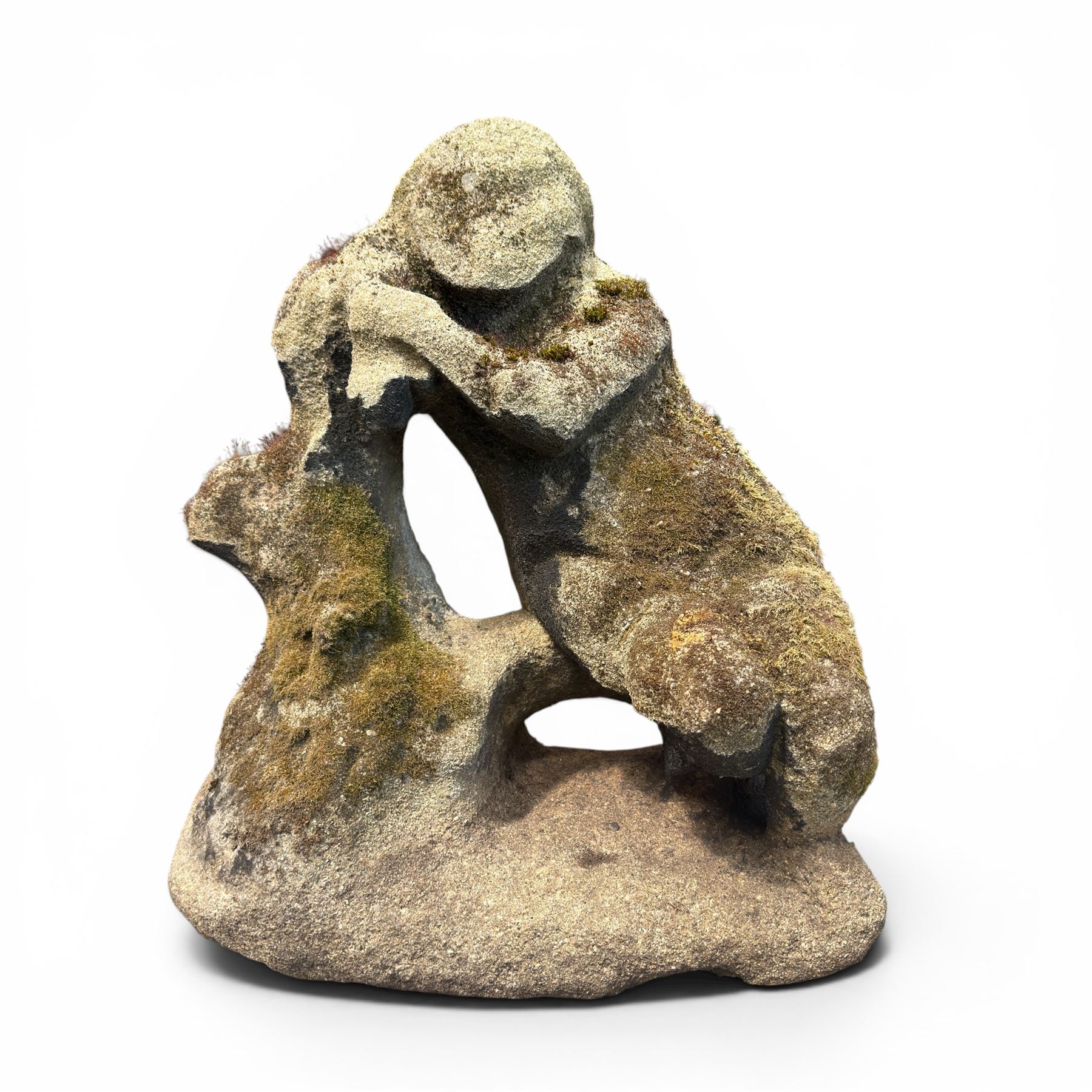 Carved composite stone garden figure, depicting a seated child with folded arms, weathered finish with moss and lichen growth, raised on an integral naturalistic base