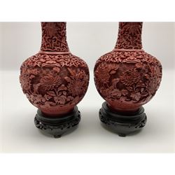 Pair of Chinese cinnabar lacquer vases, each of bulbous baluster form, carved with peonies and foo dogs amongst scrolls, with blue enamel interior and upon wooden bases, H20cm