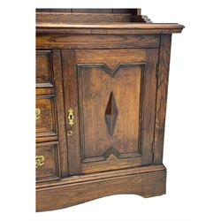 Late 19th century oak dresser, the upper section with two shelves beneath a shaped cornice, the lower section with a central bank of three drawers flanked by cupboard doors, all decorated with geometric diamond motifs, the drawers fitted with brass handles, raised on a shaped plinth base