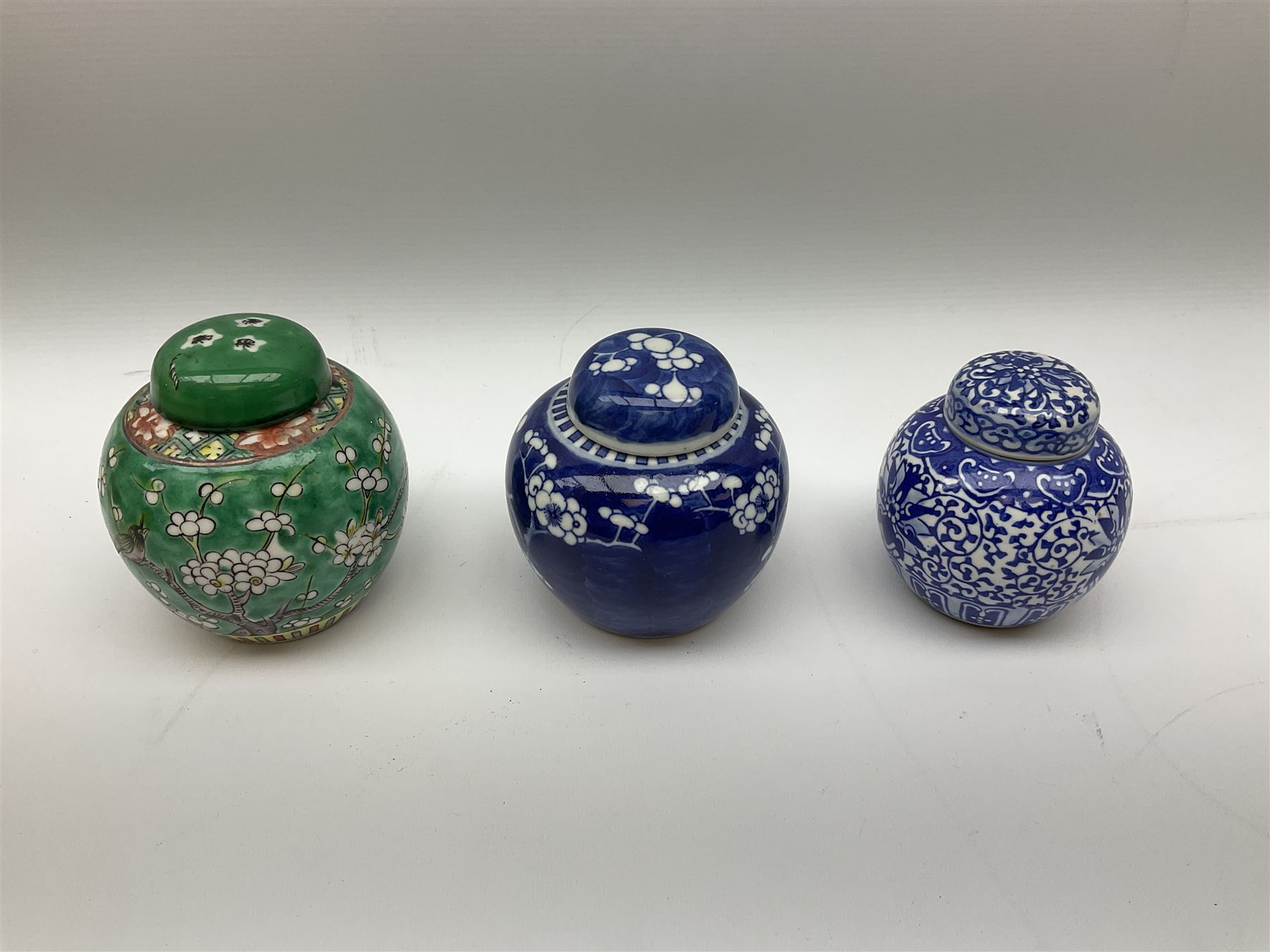 Six Chinese ginger jars, predominantly of blue and white design decorated with blossoming branches, all with lids, housed on various hardwood carved stands, some with character marks beneath