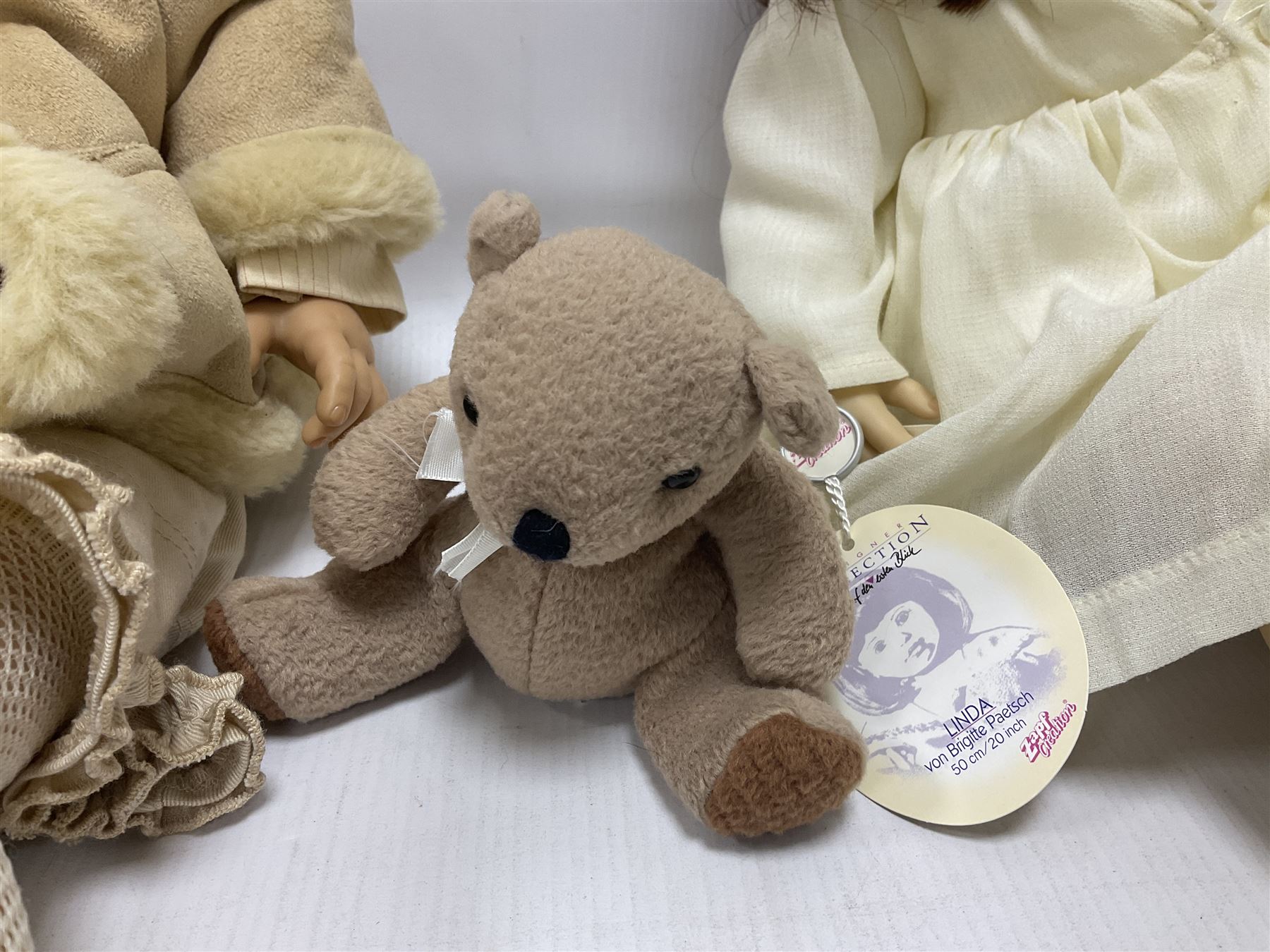Two Zapf Creation limited edition designer collection dolls, by Brigette Paetsch, the first example with faux suede jacket, red jumper and denim skirt, no. 460, the second example 'Linda' in white dress with teddy bear accessory, no. 785, each signed B Paetsch, tallest L60cm