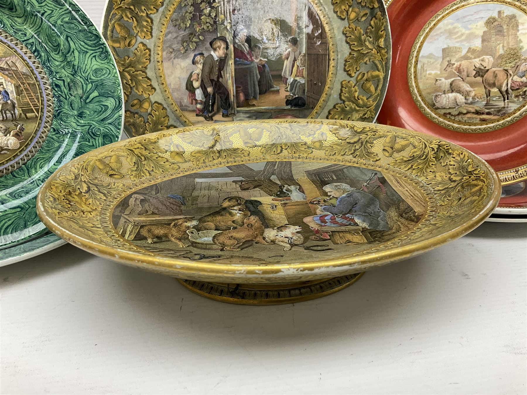 19th century Prattware table ware to include an oval footed dish decorated with a scene after Landseer 'Highland Music', retailed by James Muggleton L27.5cm, ‘The Truant’ plate after T. Webster, 'Blind Man's Buff' & 'Snap Dragon' tea plate, two side plates with malachite printed borders and others (17)
