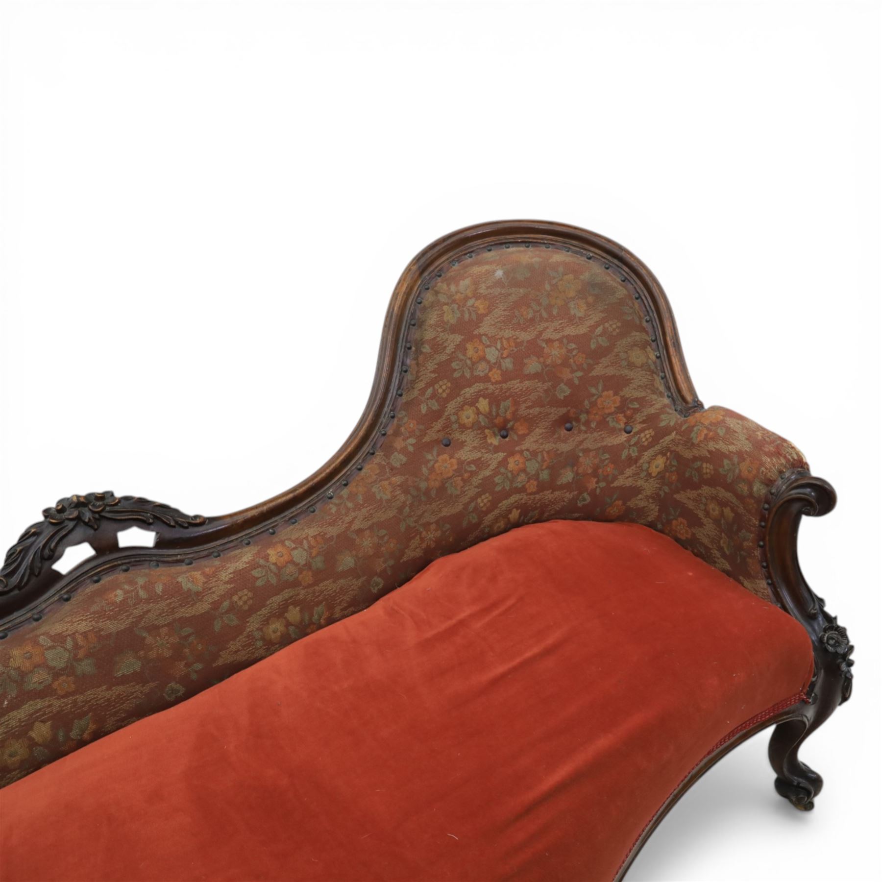 Victorian mahogany framed serpentine sofa, the shaped button upholstered back with central carved foliate cartouche, and scroll arms with carved terminals, over upholstered red seat, upon carved cabriole supports with castors