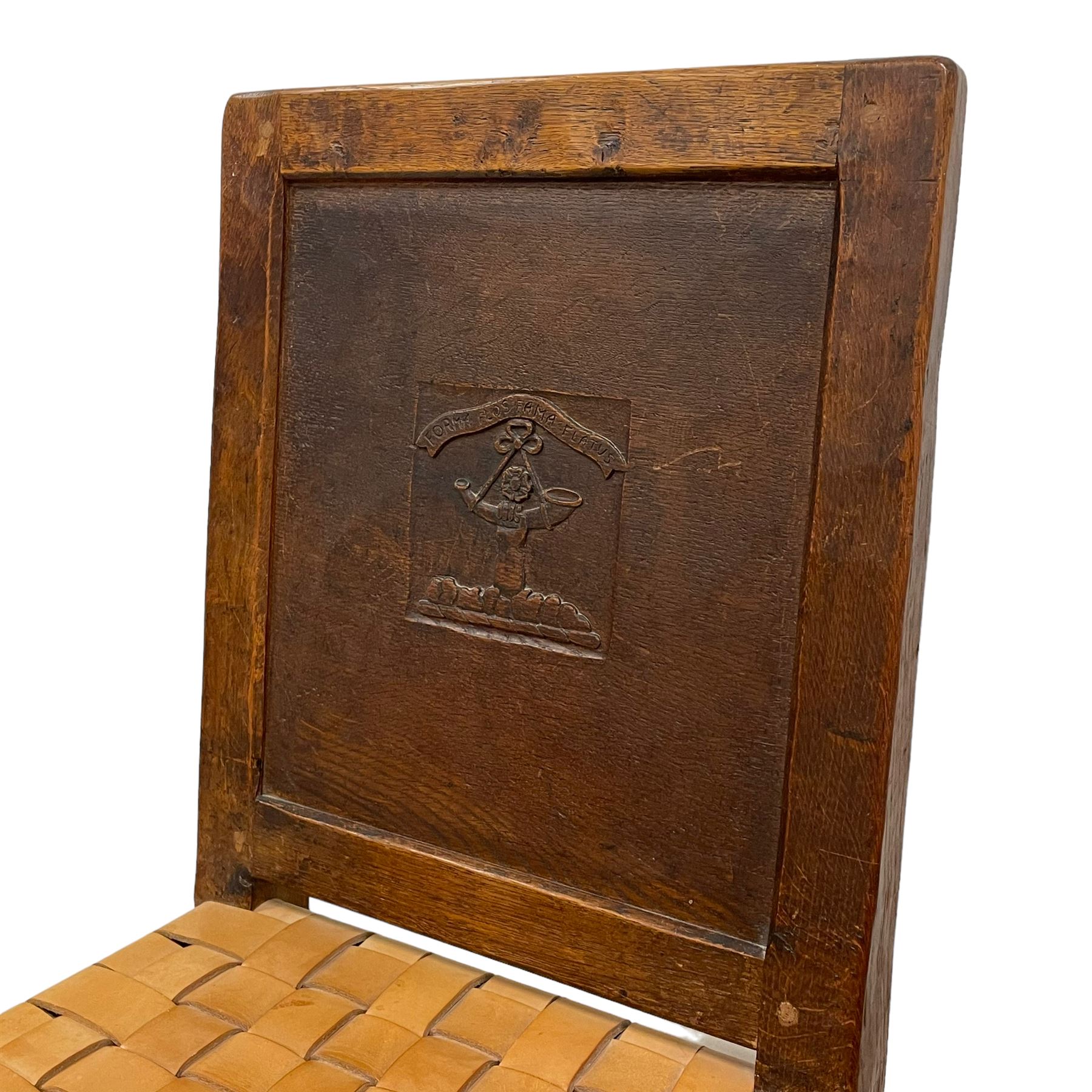 Mouseman - circa. 1930s set of six (4+2) oak dining chairs, panelled back carved with the Bagshawe family crest, the moto 'Forma Flos Fama Flatus' over an arm grasping a bugle-horn with ribbon tie and Yorkshire rose motif, adzed frame, leather lattice strap seat, on octagonal supports united by stretchers, two carvers and four side chairs, each carved with mouse signature, by Robert Thompson of Kilburn 

Provenance: Owned since manufacture by the Bagshawe family, descendants of the Staithes Group Artist Joseph Richard Bagshawe RBA (1870-1909).