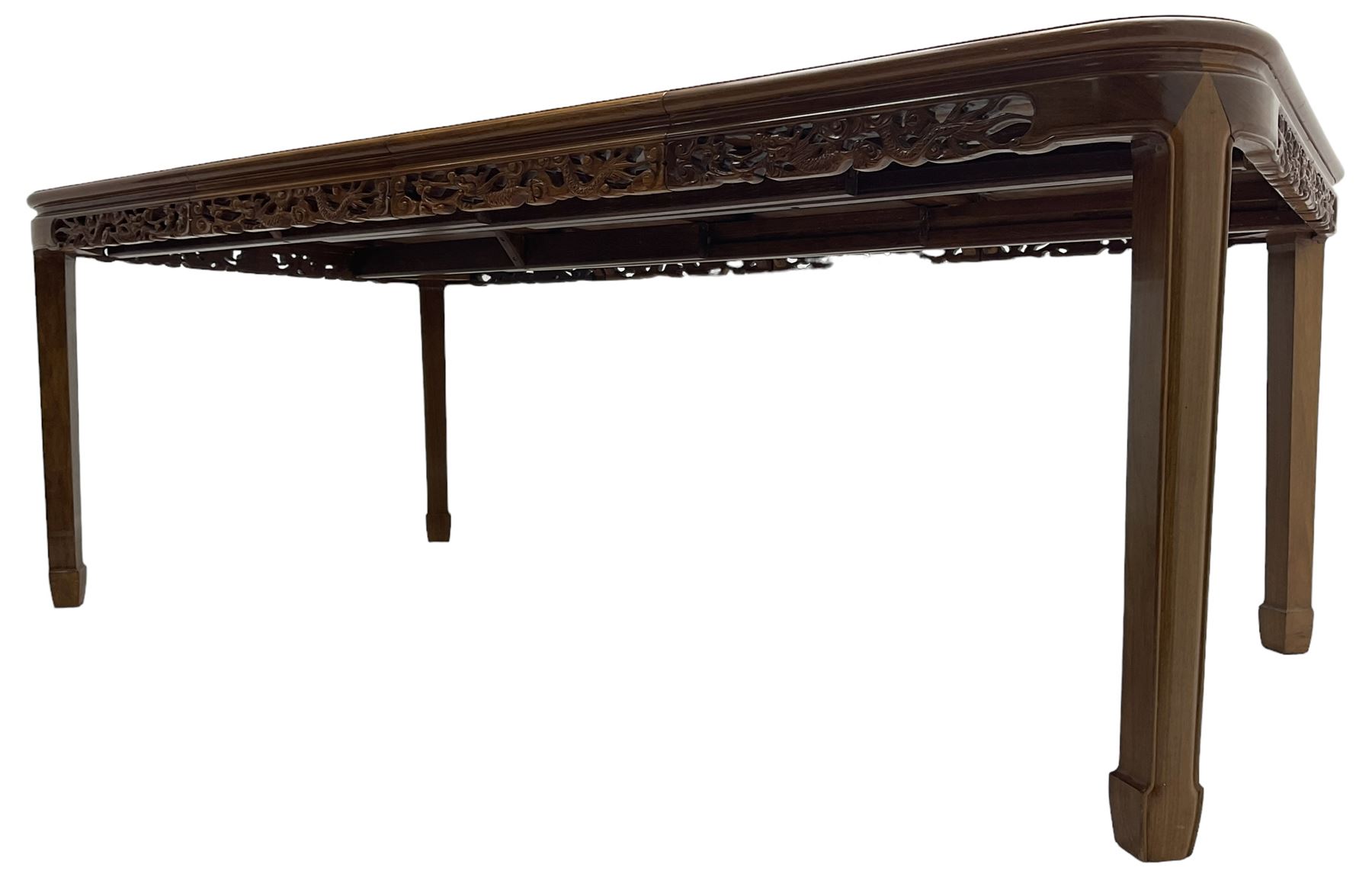 Late 20th century Chinese carved hardwood extending dining table, rectangular panelled top with rounded corners over a pierced frieze carved with dragon motifs and scrolling foliate decoration, with two additional leaves