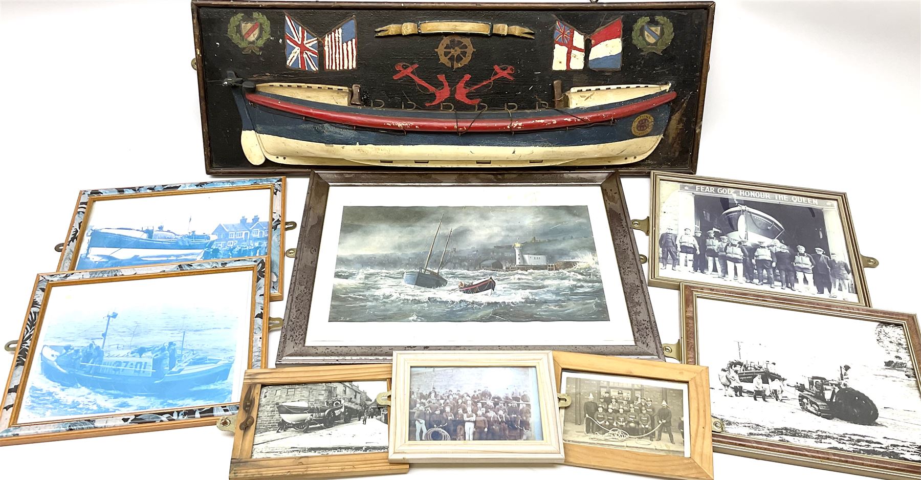 RNLI collection box in the form of a boat makers half block model, painted in the colours of a lifeboat with flag and ship motifs, H25cm, L73cm together with framed photos, postcards and prints of lifeboats and crew, including Scarborough lifeboat station