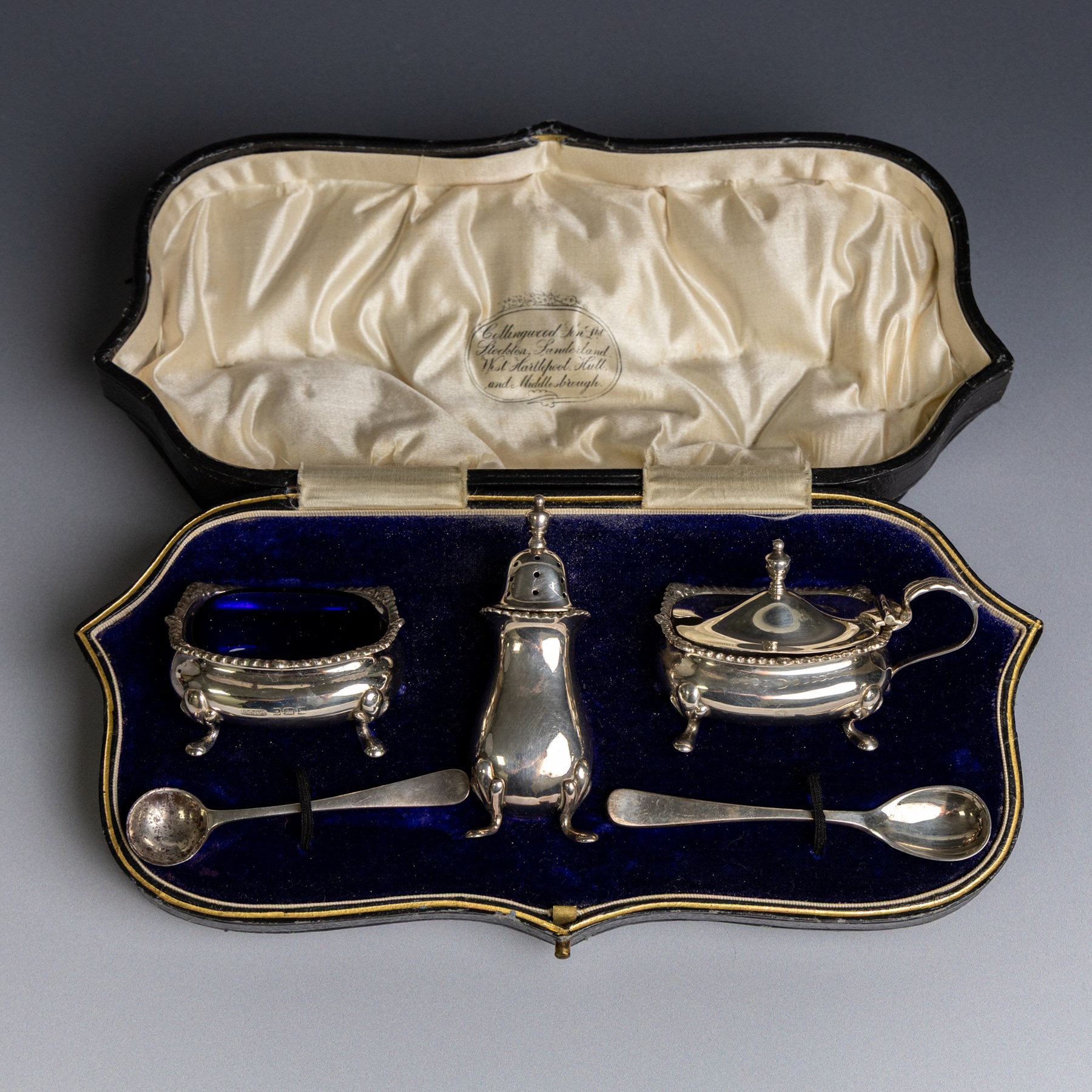 1920s silver three piece cruet set, comprising mustard pot and cover, pepper shaker and open salt, together with two matched silver cruet spoons, all hallmarked, contained within fitted tooled leather case