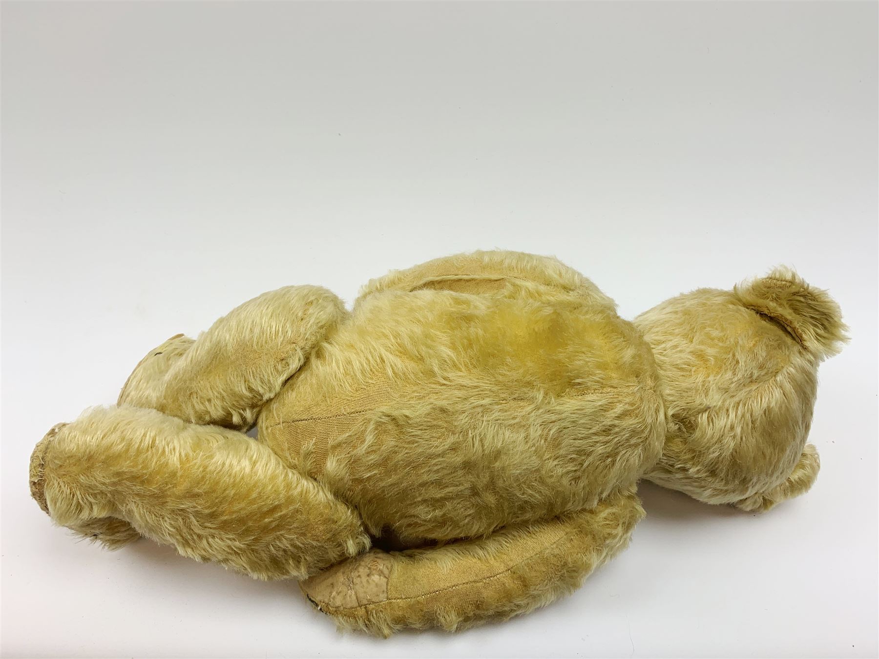 Chad Valley large teddy bear c1930s with wood wool filled blond mohair body, jointed swivel head with glass eyes, shaved muzzle with vertically stitched nose and mouth and jointed limbs H21