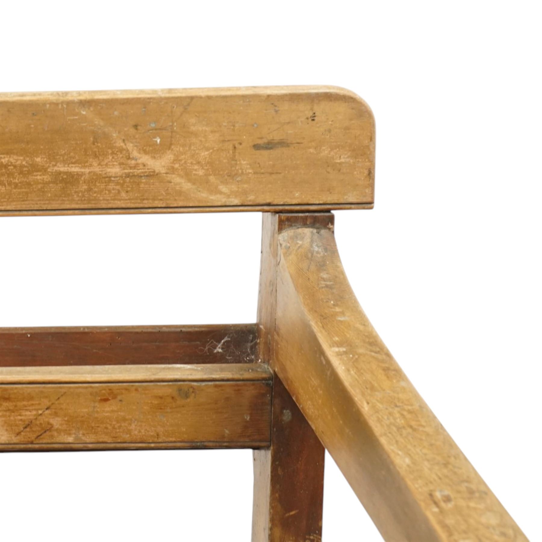 Early 20th century pine chapel bench, with moulded plank back rail over plain rail, with book storage to the back, open shaped end supports with curved arms, turned front uprights, plank seats, square legs united by low stretchers
