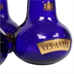 Set of four 20th century Royal Pharmaceutical Society blue glass bottles, of bellied form with clear cut glass spire stopper, each body bearing gilt label in Latin: VIN:ACET:, VIN:ANTIM:, VIN:XERIC:, and VIN:FERR:, and gilt Royal Pharmaceutical Society crest to neck, H25cm

Provenance: From the collection of the family of Peter Green, a practising pharmacist whose career spanned the mid to late 20th century. During his professional life he managed pharmacies in Yeovil, Somerset, and later Selles Chemist in Filey, North Yorkshire, before purchasing and running his own business, Peter Green Pharmacy, located in the Market Place, Malton. The bottles were displayed as part of the traditional shop fittings in both the Filey and Malton pharmacies and were retained as part of his collection.