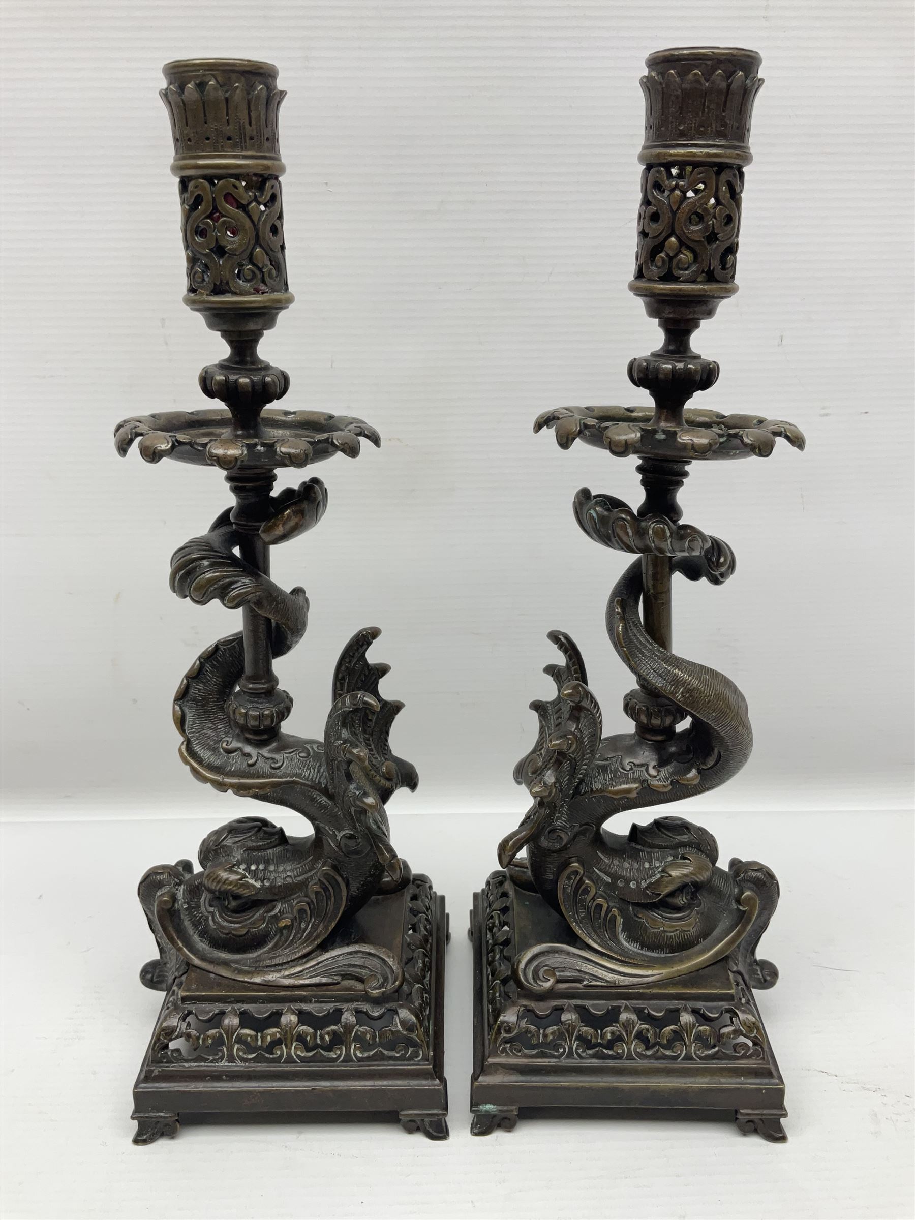 Pair of late 19th/ early 20th century brass candlesticks in the form of dolphins upon a stepped base with Fleur-de-lis design, H32cm 