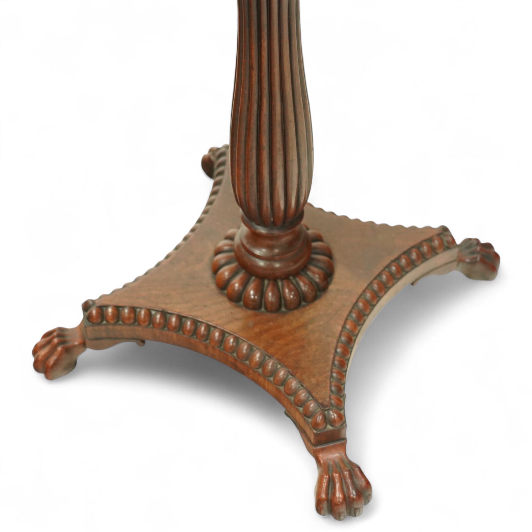 William IV mahogany folding card table of unusually small proportions, rectangular swivel top with gadrooned edge, raised on a slender tapered reeded column over quatreform base with gadrooned border, terminating in carved lion paws feet