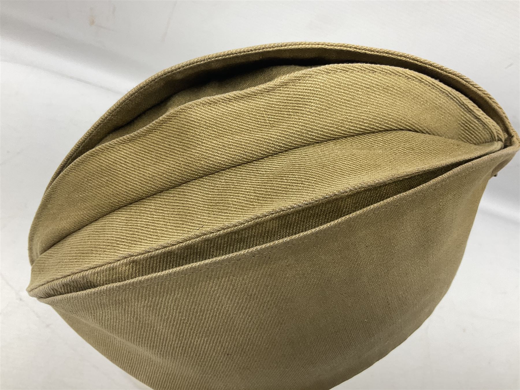 Four side caps - WW2 Russian, post-WW2 Russian and two East German; all with badges, one with multiple metal badges (4)