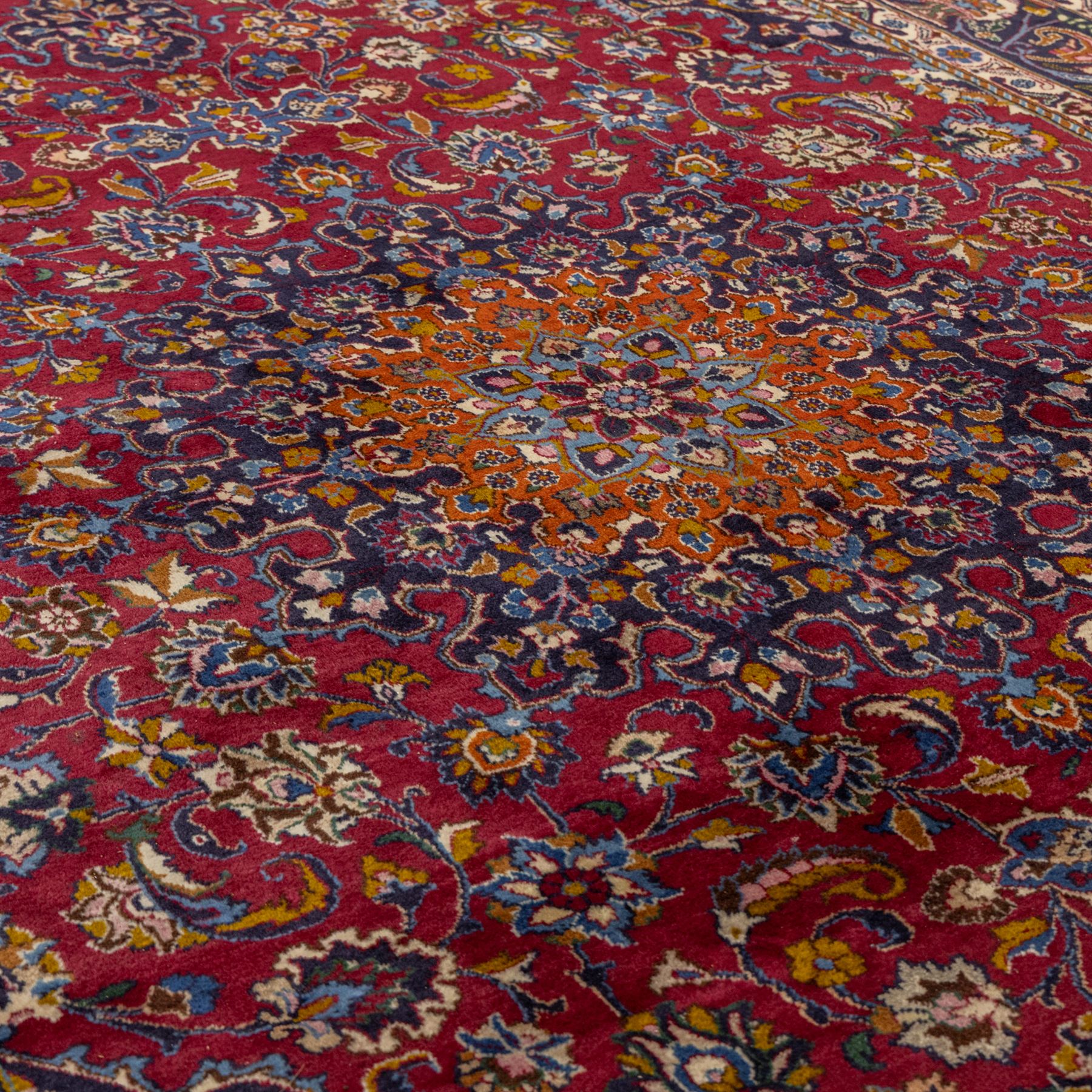 Persian Kashan wool carpet, red field centred with large floral medallion and conforming pendants, decorated with scrolling foliage and flowerheads, indigo spandrels and borders, from the region of Kashan