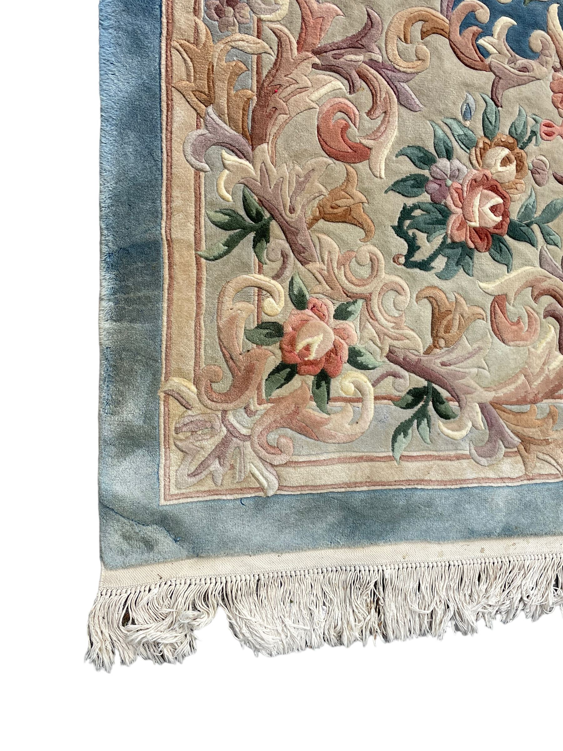 Large Chinese blue ground woollen carpet, overall floral design, central oval medallion surrounded by scrolling floral decoration, wide border with decorated with floral bouquets 