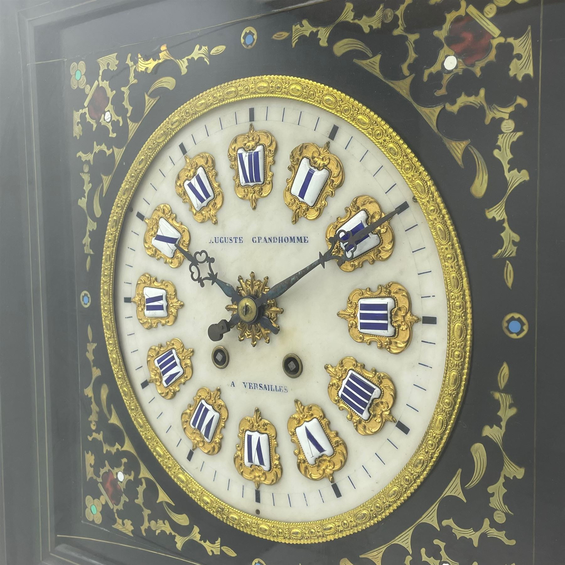 Auguste GP. Andhomme - French vineyard clock,  late 19th century 8-day twin train spring driven wall clock with enamelled and inlaid brass decoration within an ebonised and glazed case, circular enamel dial with cartouche Roman numerals, minute markers, pieced steel hands and a chased brass slip, striking movement, sounding the hours and half hours on a coiled gong. With pendulum and key.  
