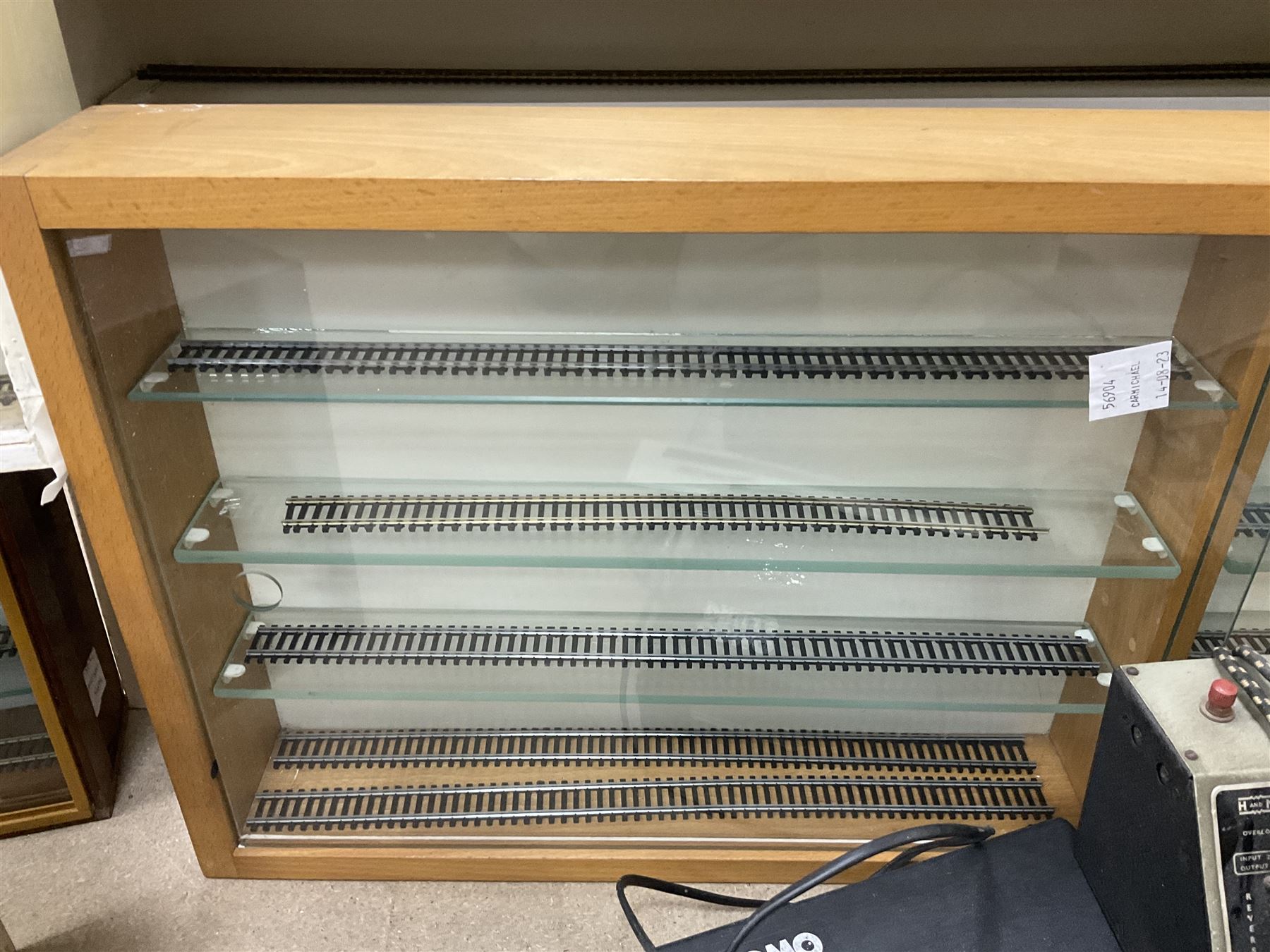 Six shelved cabinets for displaying ‘00’ gauge locomotives comprising plain plywood and white painted examples with track applied to various shelves, largest H63cm, W107cm, D27cm; Collection of tools for building model locomotives to include Weller PU-2D Soldering Pencil and Standard Tip Soldering Iron 20W/230V, Humbrol Modellers Airbrush, Power Supply Units and two wooden chests one of which housing a collection of tools including tweezers, scalping tools, wrenches etc 