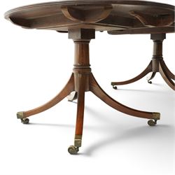 George III mahogany twin pedestal extending dining table, the twin D-ends with additional leaf, raised on twin turned pedestals terminating to four splayed supports with brass cups and castors