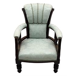 Late Victorian carved mahogany open armchair, the shaped back with fluted upholstered panel and padded arms above pierced scroll carved side supports, over a broad upholstered seat, on turned front supports