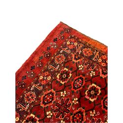 Persian red ground rug, the field decorated with lattice pattern and flowerhead, repeating border decorated with flower heads and leaf motifs
