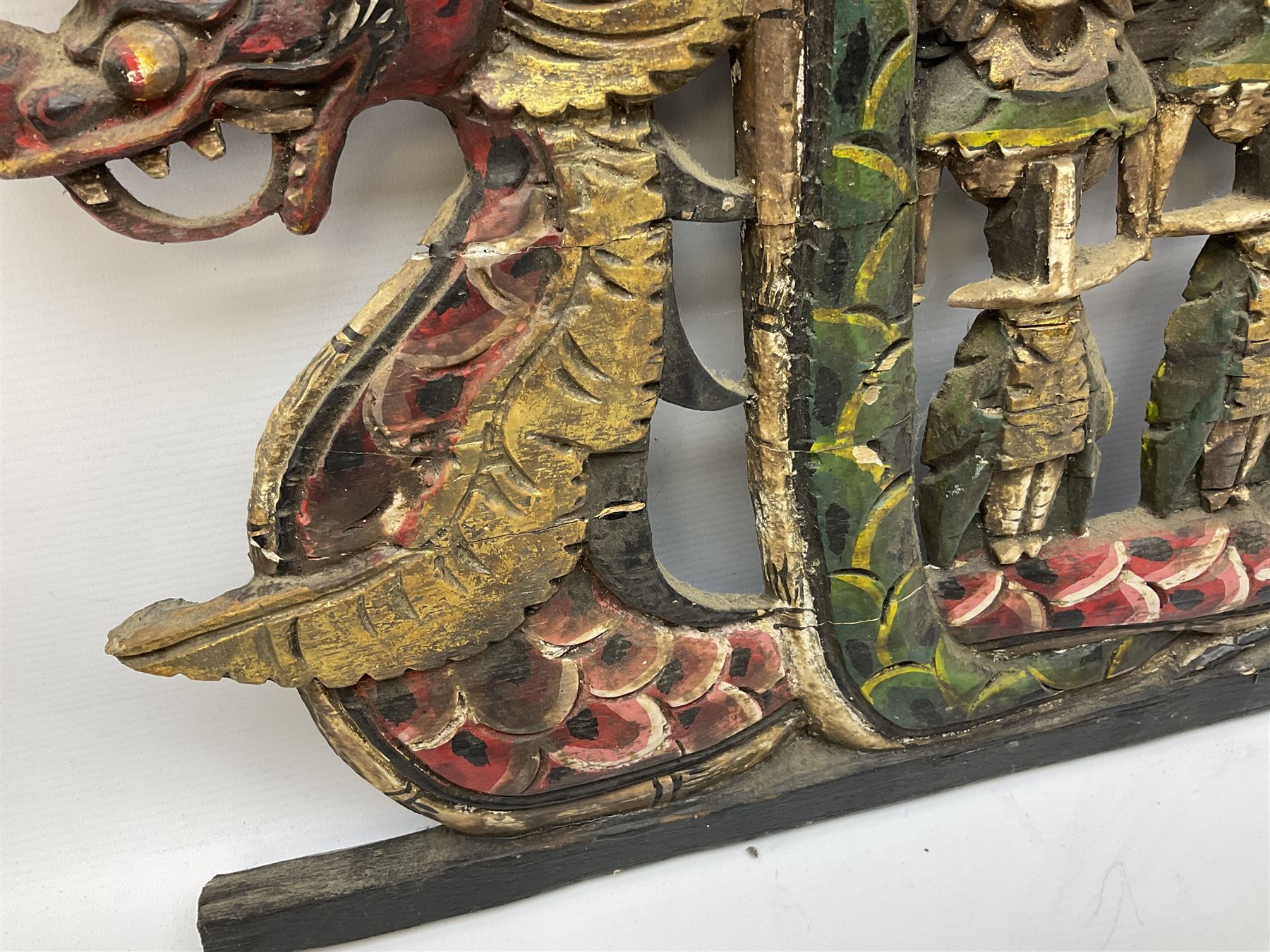 Balinese wood wall panel carved as a dragon boat with passengers, painted in reds and greens with gilding, together with a carved wood figure of Ganesh Deity decorated with gilt, raised upon circular lotus flower plinth, H78cm