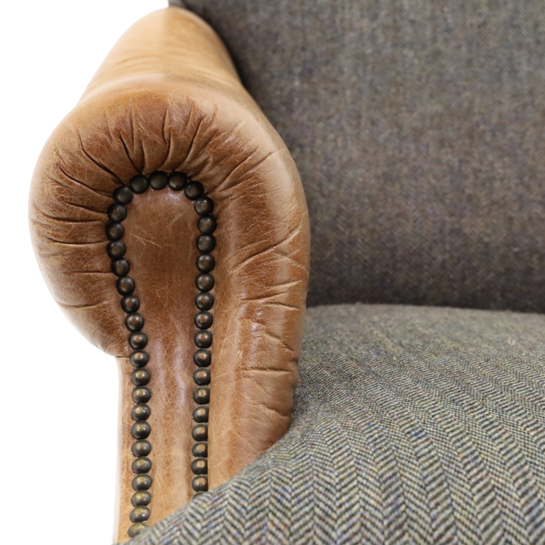 Tetrad - 'Taransay' Harris Tweed and tan leather club armchair, Howard shape with reclined back over deep seat and rolled arms with studwork, raised on turned front supports with castors, the sides and arms upholstered in tan leather with seat and back in herringbone-stitched Harris Tweed