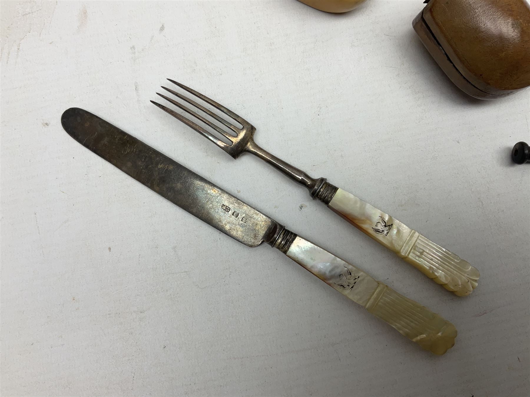 Swiss mountain hunters tobacco pipe with a horn mouthpiece, metal hinged pierced lid and brass chain, the black coated body adorned with small metal cow flowers, together with two other pipes and case, brass mounted horn, brass mounted bone box, carved mother of pearl handled knife and fork and brass jug