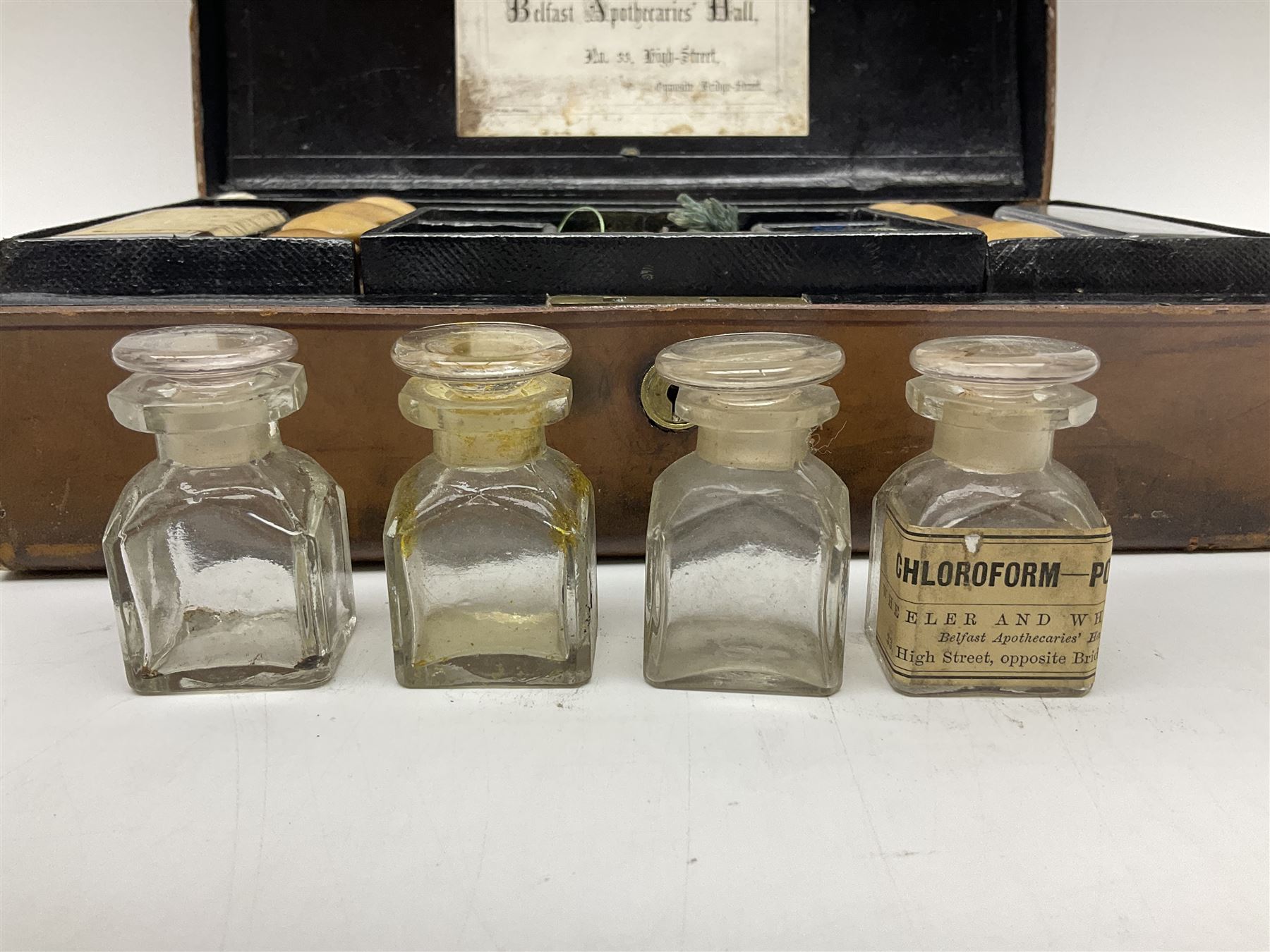 19th century apothecary leather carrying case, with key, the hinged lid opening to reveal seventeen glass medicine bottles with stoppers, most with chemist labels, gram scales, and domestic medicines booklet, H9cm, L27cm