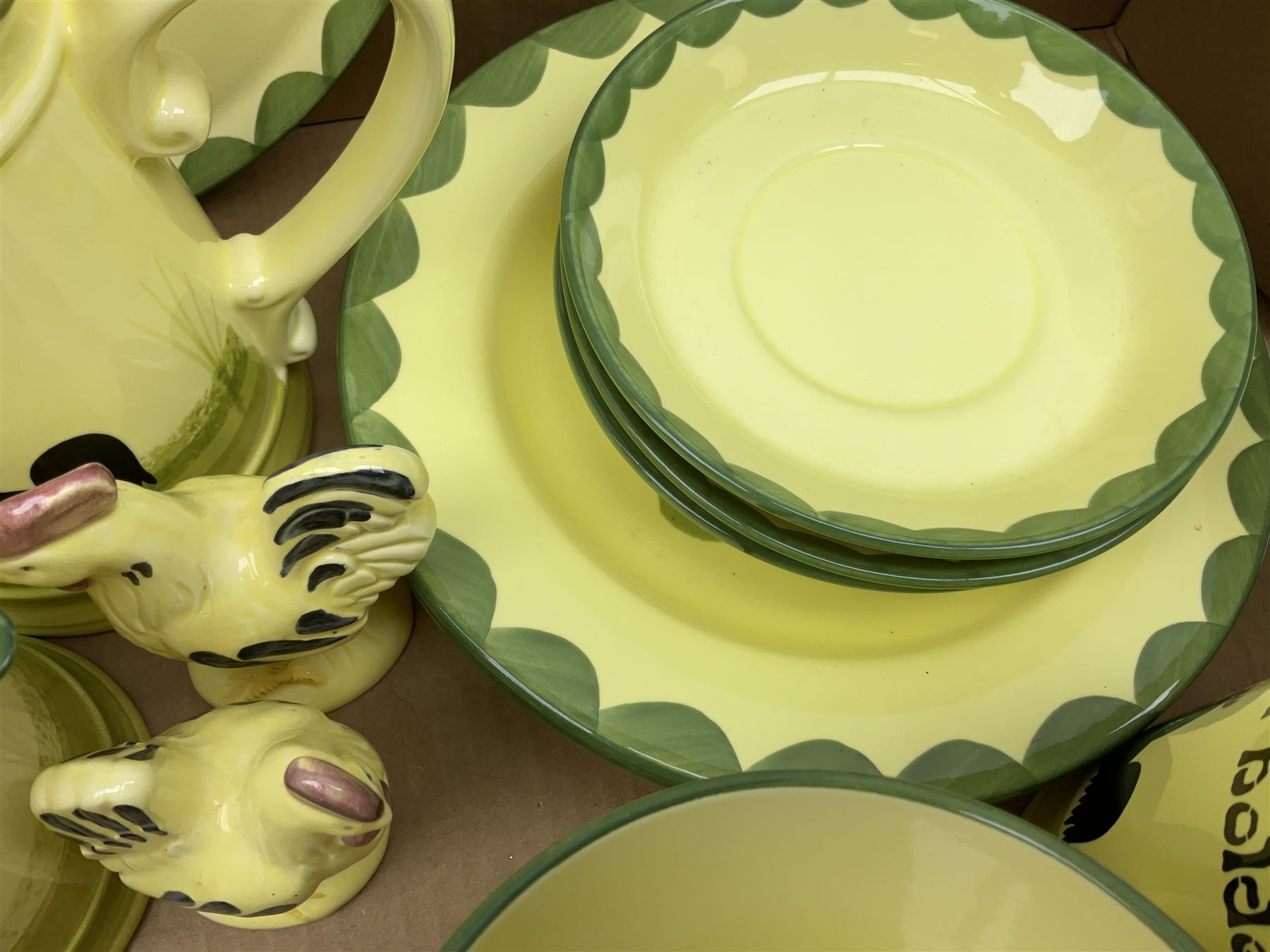 Zeller Fayencerie dinner and tea wares, decorated in cockerels against a yellow ground, with green scalloped border, comprising cake stand, two plates, bowl, three large teacups and saucers, coffee pot, milk jug, cream jug, lidded sugar bowl, pair of cruets modelled as cockerels, butter dish and cover, and utensils pot, and four similar egg cups, in one box 