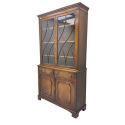 George III design mahogany bookcase on cabinet, projecting dentilled cornice over two astragal glazed doors, lower section fitted with two drawers with lion mask handles over double cupboard, on plinth base