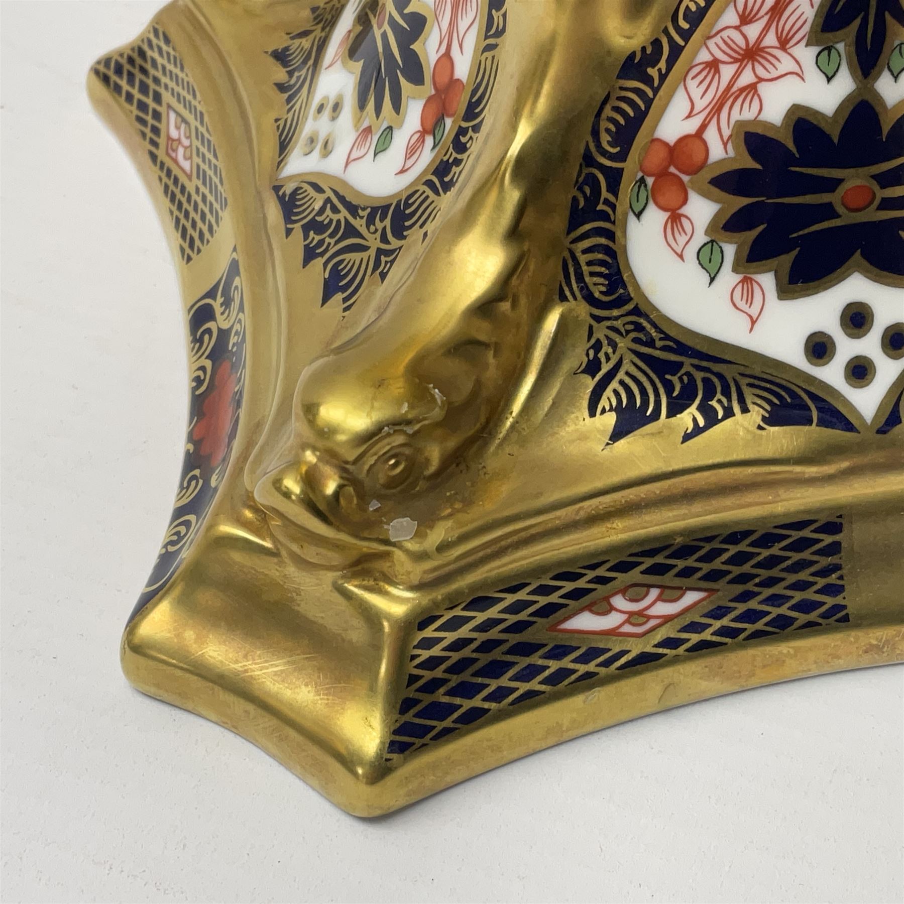 Pair of modern Royal Crown Derby Old Imari 1128 pattern candlesticks, each with shaped drip tray affixed to squat socket, upon spreading stem and canted square base with gilt dolphin edges, with printed marks beneath including Roman numeral year cypher for 2003, H26.5cm, with original boxes