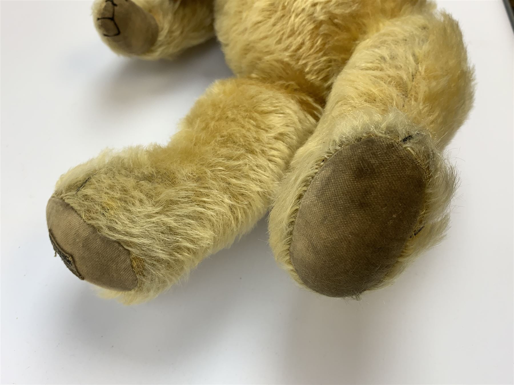 Merrythought Hygienic Toys large 'Magnet' teddy bear c1930s with plush body, swivel jointed head with glass eyes and vertically stitched nose and mouth and jointed limbs,  celluloid wishbone button to right ear and stitched label under right pad H22