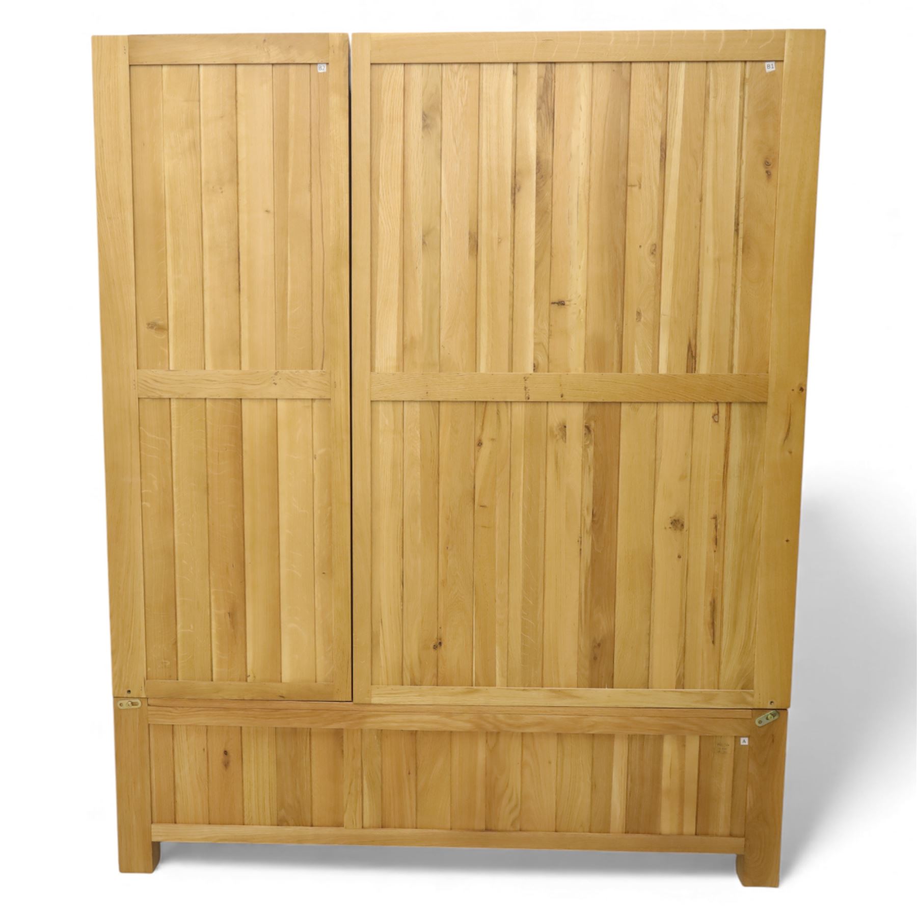 Modern light oak triple wardrobe,  three panel doors with integrated handles enclosing full-height hanging rails, the lower section fitted with two flush-front drawers, square uprights