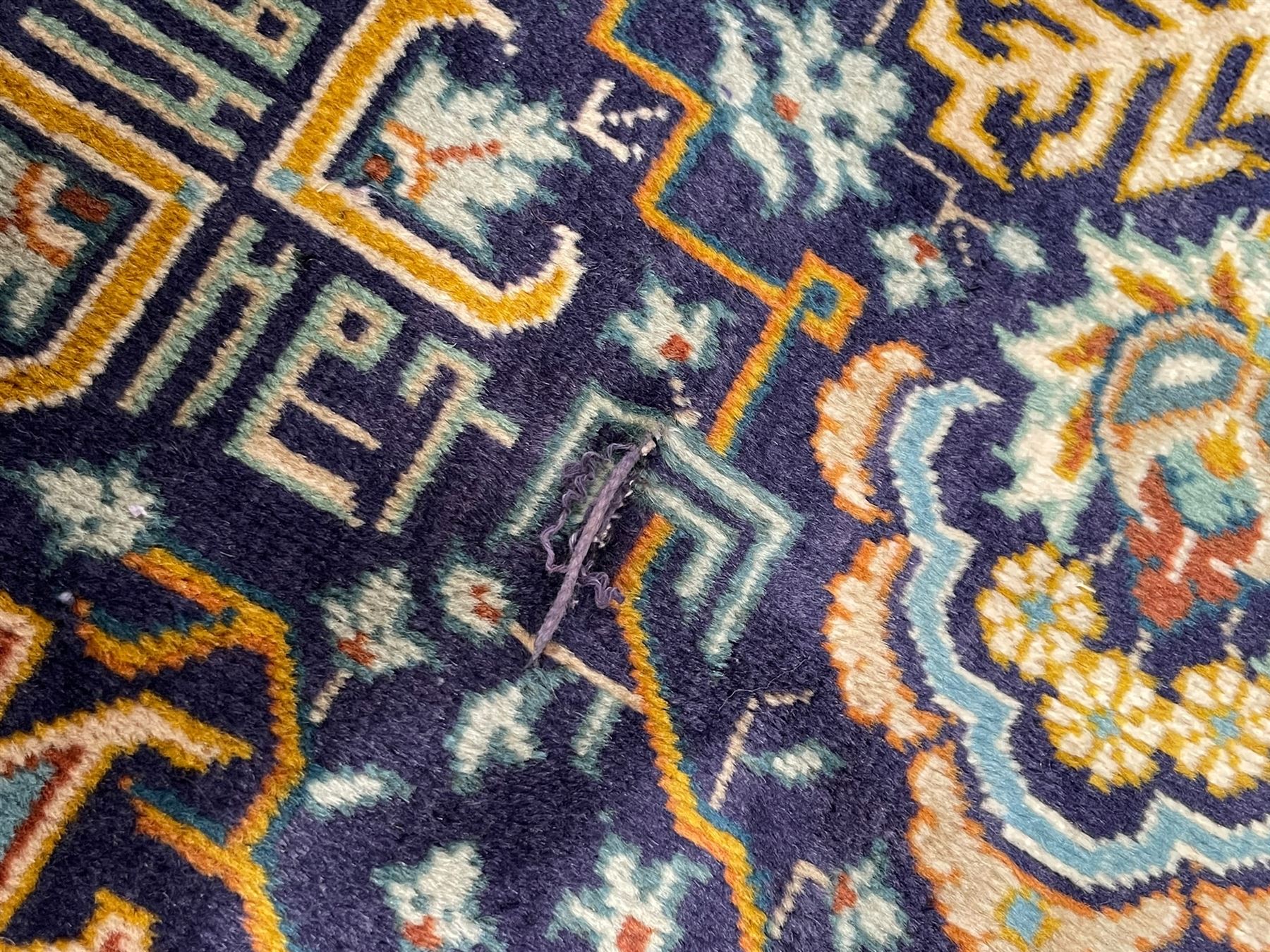 Persian indigo and pale gold ground rug, overall busy geometric design, the field decorated with hooked Hac and palmette medallions surrounded by densely patterned zig-zags and stylised foliate motifs, the border decorated with smaller Hac motifs, within multiple guard stripes 