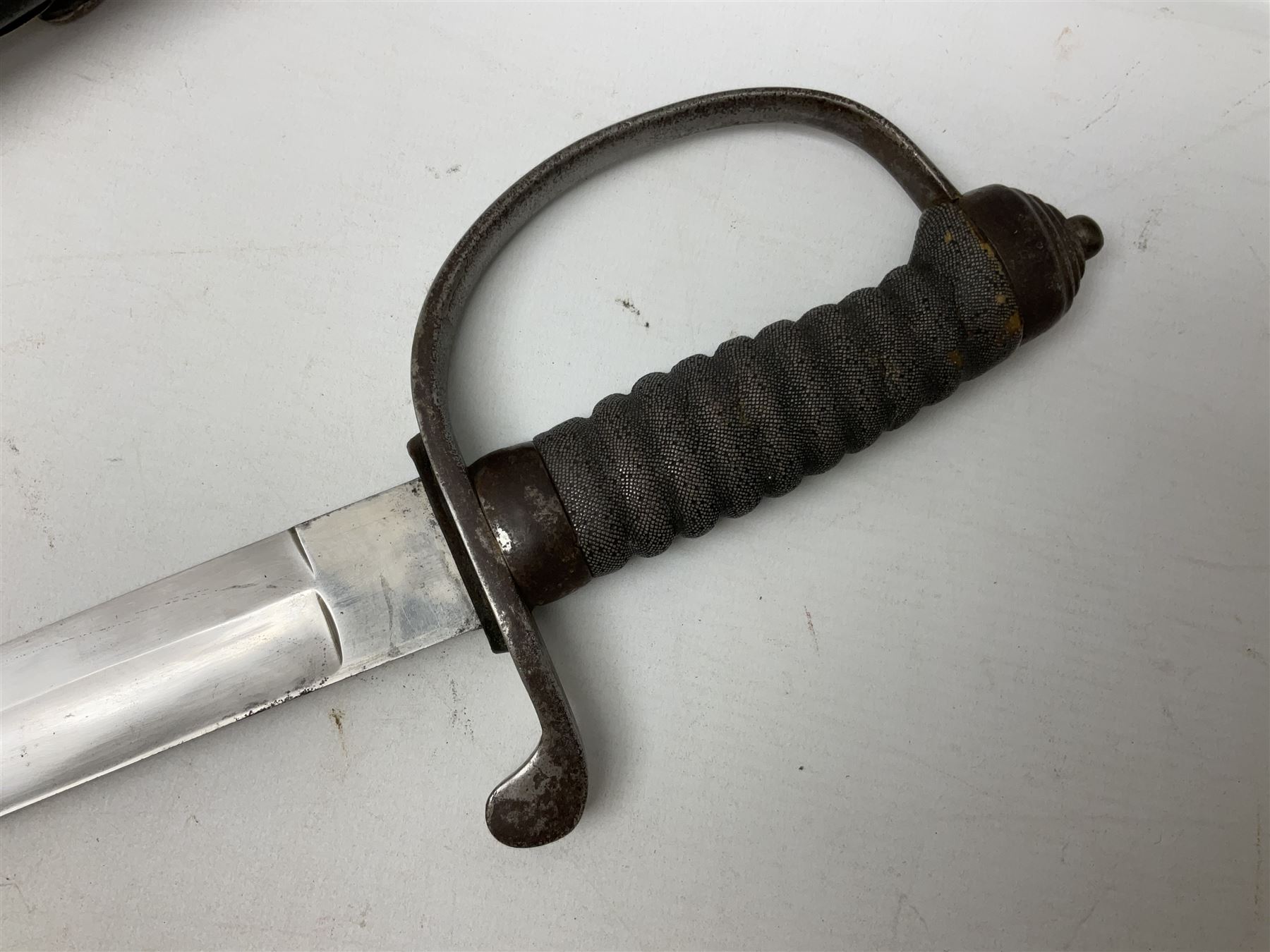 Mid-19th century Custom’s officer/Constabulary sidearm, with plain 60.5cm slightly curving fullered blade double edged at tip,  steel knucklebow and downswept quillon, stepped pommel and ribbed fishskin grip; in leather covered scabbard with steel locket, frog stud and chape L76cm overall