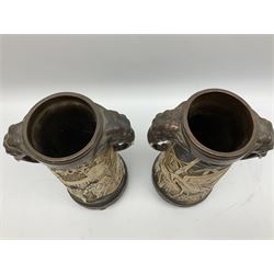 Pair of Bretby vases of tapering cylindrical form decorated with elephants, cranes and fishermen, the bodies with twin elephant mask handles, with coppered borders, raised upon three bun feet, stamped Bretby 2246 marks beneath, H32cm