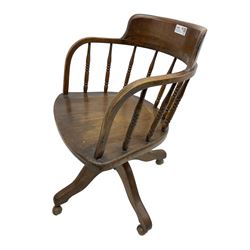 Early 20th century oak framed swivel Captain's chair, tub shaped back with turned spindle supports over saddle shaped seat, quadriform base on castors