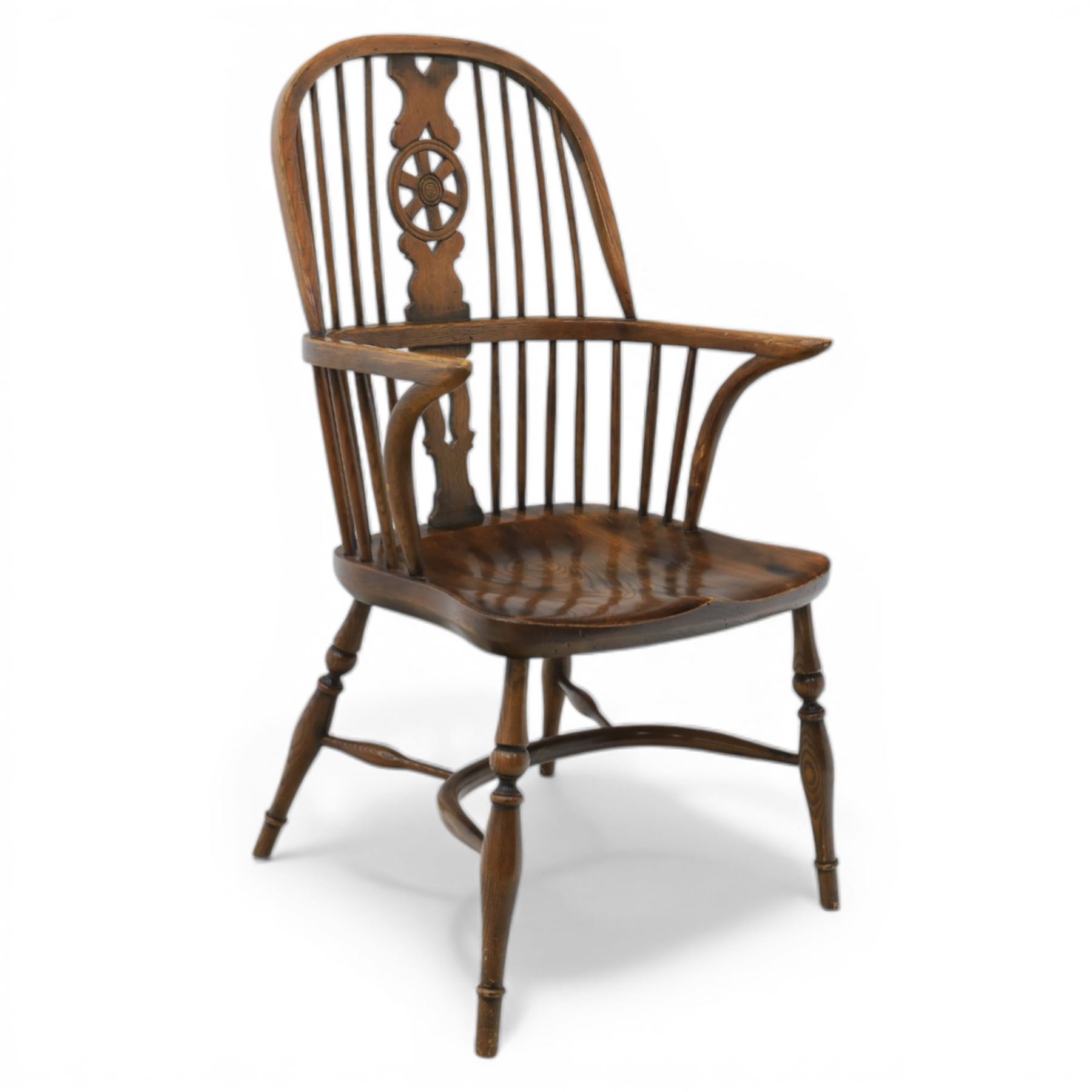 Late 19th century stained elm and beech Windsor armchair, the arched hoop back with pierced wheel splat above shaped lower splat between turned spindles, shaped arm rail on turned supports, saddle seat, raised on turned legs united by a crinoline stretcher