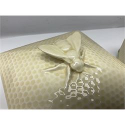 Four square honey boxes with lids,  each decorated with honeycomb pattern and finished with a bee finial