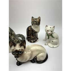 A Winstanley cat, with glass eyes in seated post, signed beneath, H25cm, together with three other figures of cats, including a Rye Pottery example. (4). 
