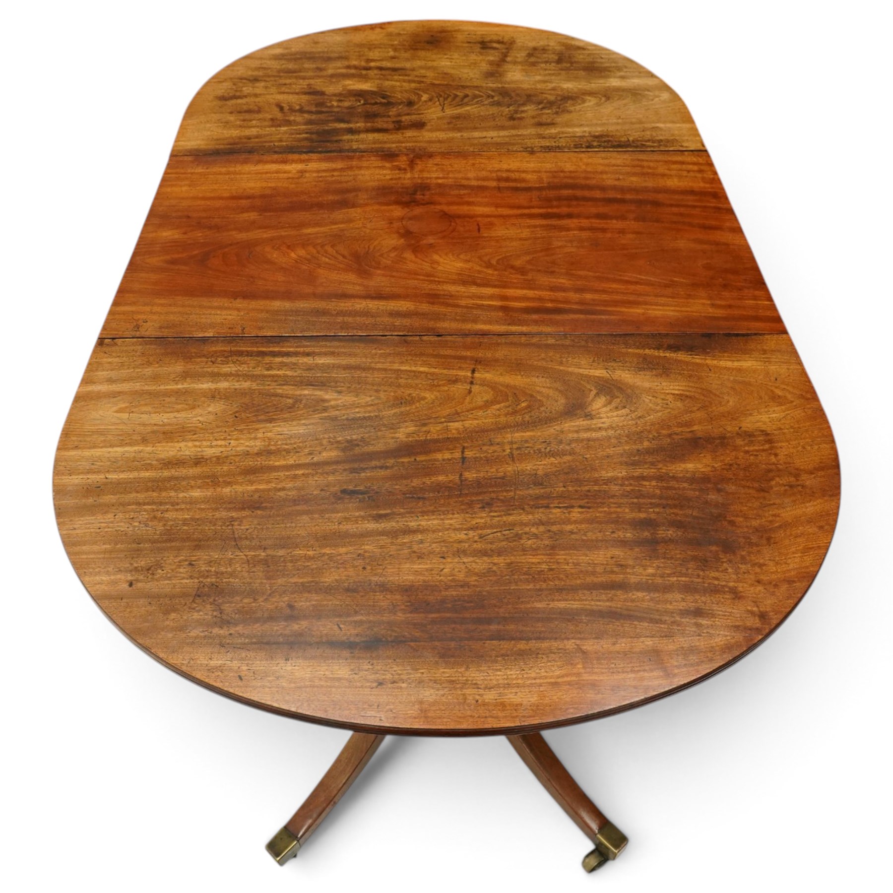 George III mahogany twin pedestal extending dining table, the twin D-ends with additional leaf, raised on twin turned pedestals terminating to four splayed supports with brass cups and castors