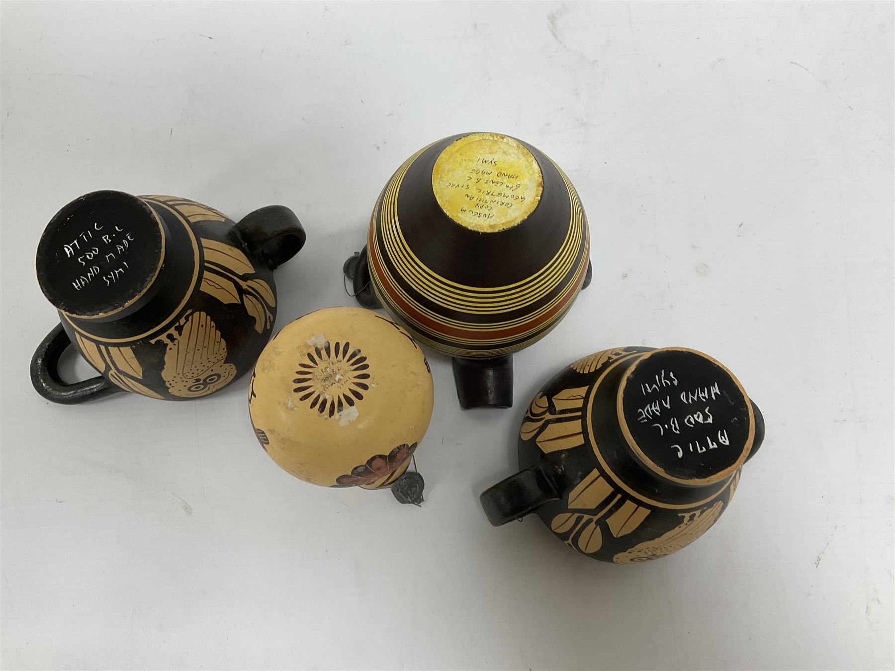 Four examples of reproduction Ancient Greek pottery, to include two skyphoi decorated with the Owl of Athena, standing between two sprays of olive in the manner of 5th century, both signed Attic 500 B.C,  terracotta twin handled vase with spout decorated in the Corinthian Geometric style, in the manner of 6th Century, signed beneath, and a further jug in the 7th Century Corinthian style decorated with flowers and birds