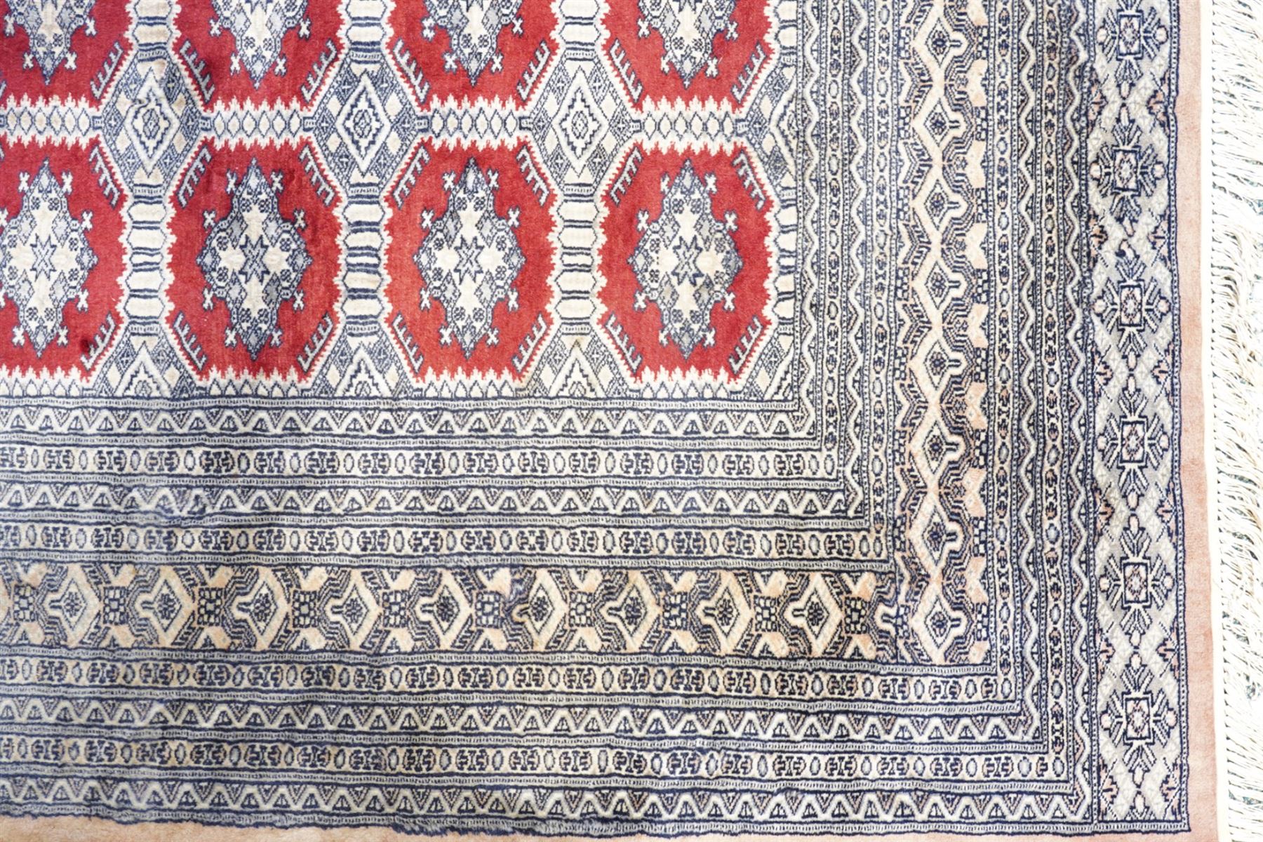 Jaldar Bokhara crimson and pale ground carpet, the field decorated with five rows of Gul motifs, within intricate multi-band border decorated with repeating geometric designs 