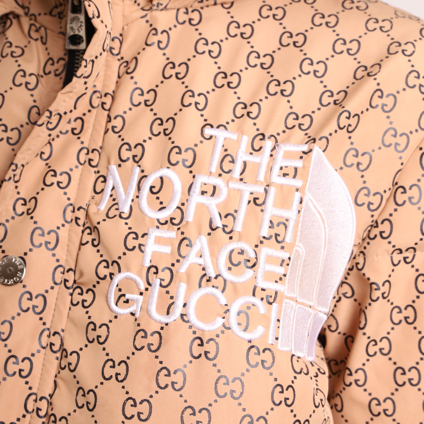 Gucci x The North Face – monogram hooded puffer jacket, beige and ebony GG monogram fabric with embroidered Gucci x The North Face logos to the chest and interior collar, detachable/adjustable hood, zip fastening with silver tone press-studs, flap pockets and vivid orange lining, size S