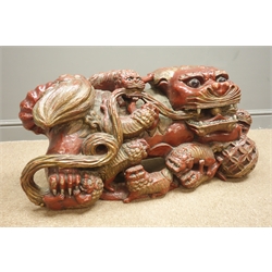  Pair of Chinese carved and red painted wood Temple Lions and  cubs, paw resting on a pierced ball, L102cm, H44cm, D38cm (2)  