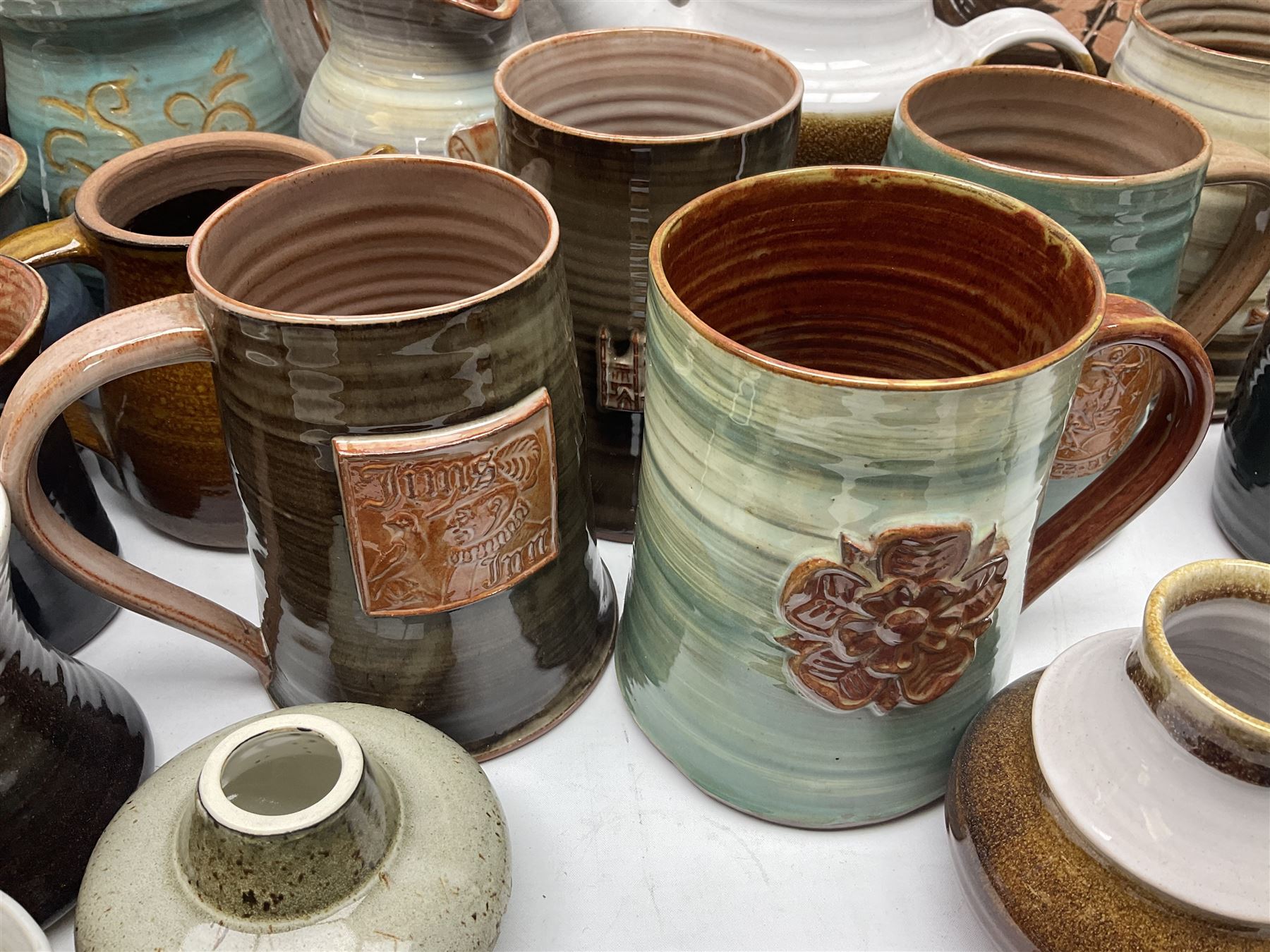 Wold studio pottery tankards, in various colours and relief decoration together with other studio items including vases, jugs and pots 