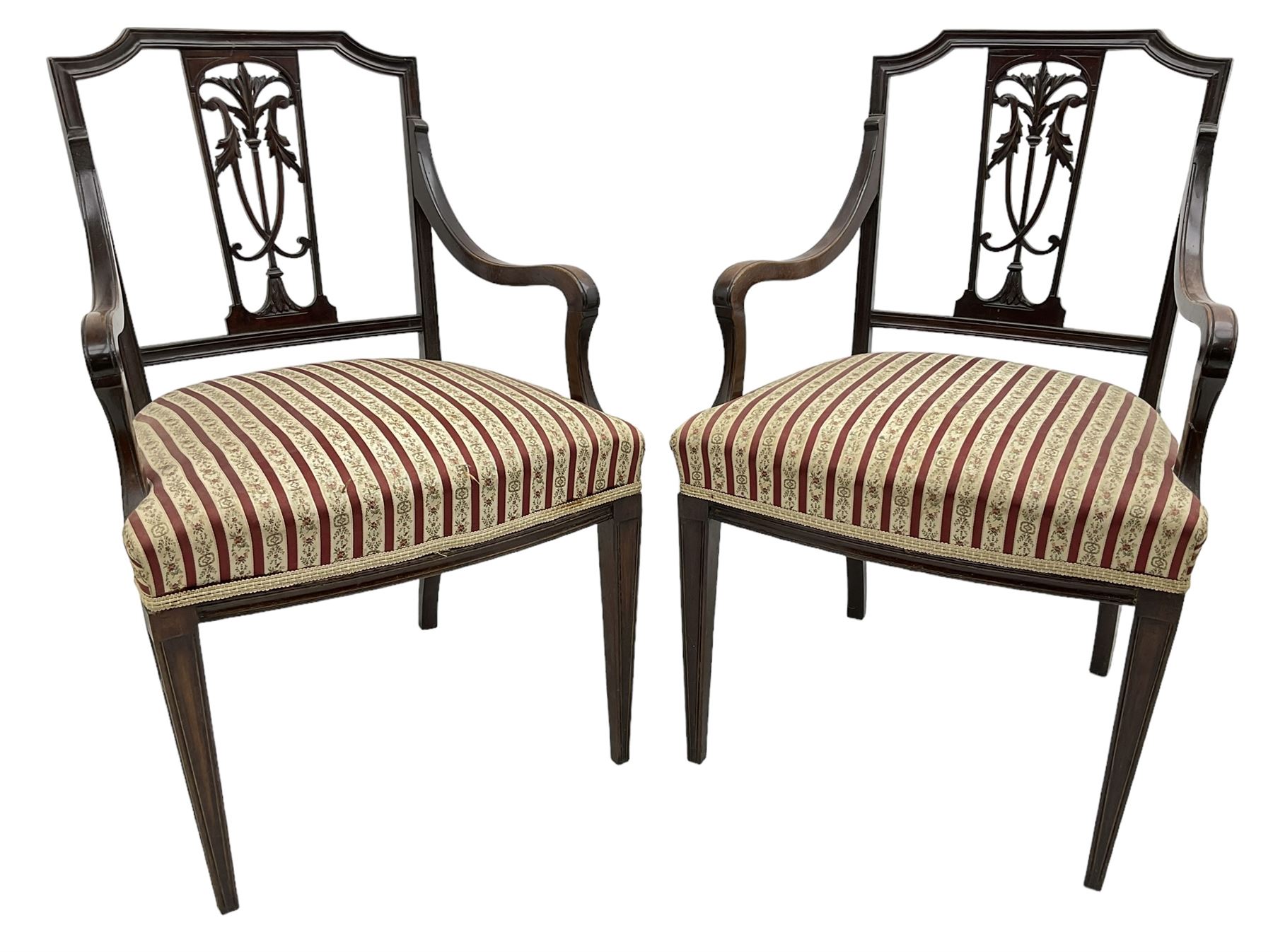 Edwardian mahogany framed three-piece salon suite - two-seat sofa, stepped cresting rail over acanthus and scroll carved pierced splat, upholstered in striped fabric (W124cm, H87cm, D62cm); and a pair of matching armchairs (W60cm) 